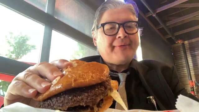 Man In Suit Eats A Hamburger